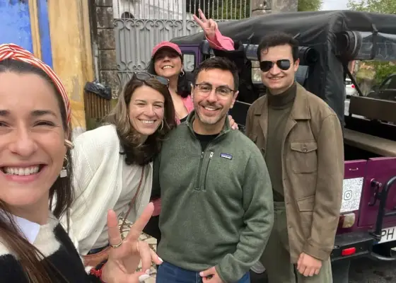 A group smiling beside a classic YourTuk jeep